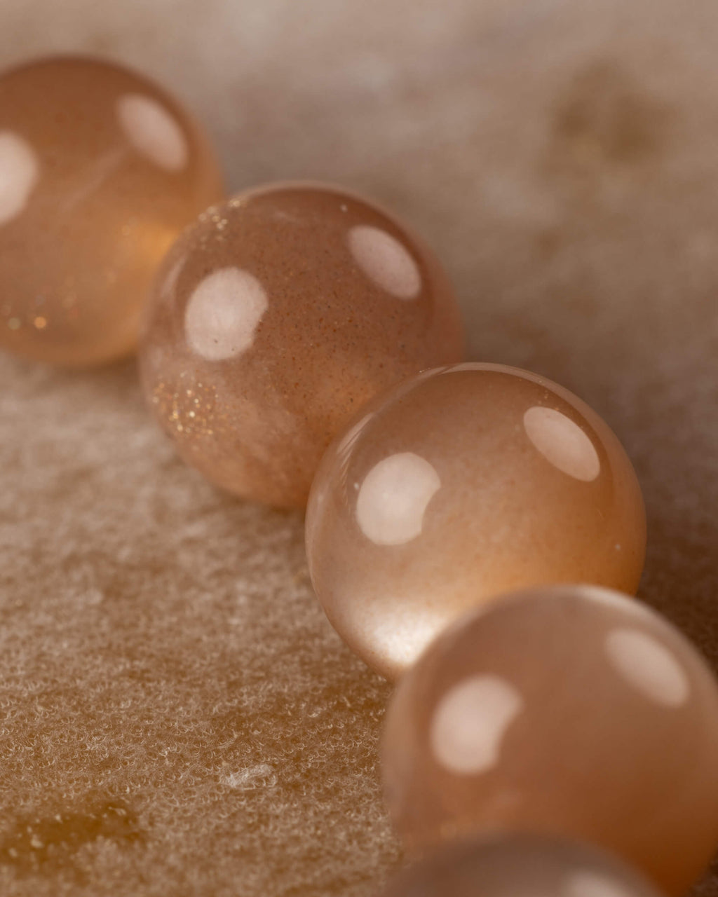 Detalle macro de las cuentas de Piedra Sol Naranja con destellos dorados y fondo claro