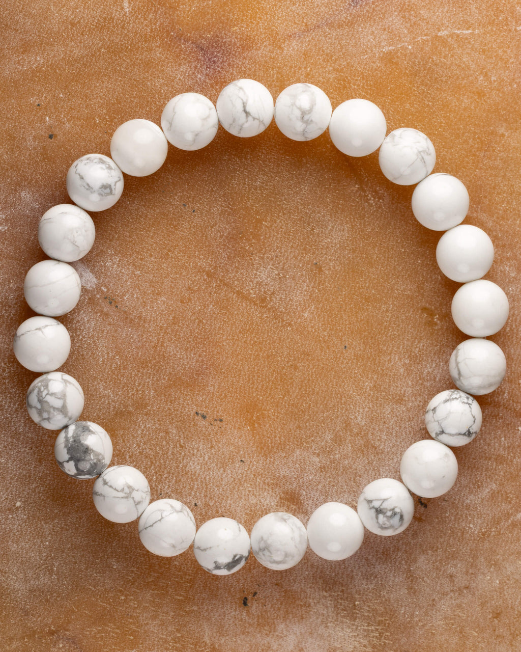 Pulsera de Howlita, pieza completa en círculo sobre superficie ambar