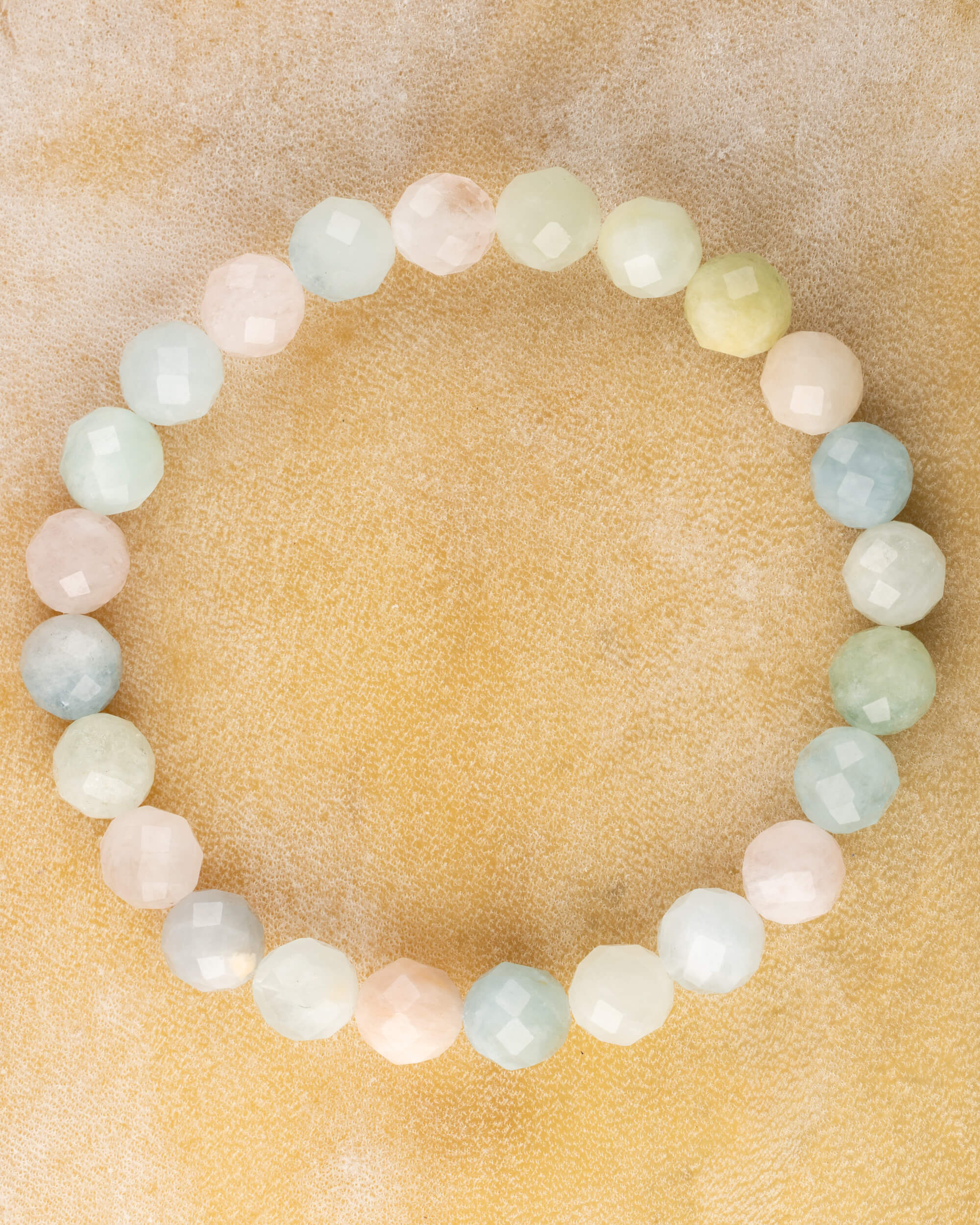 Pulsera de Berilos facetados, pieza completa en círculo sobre superficie dorada