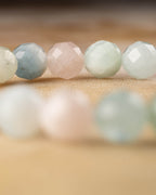 Cuentas facetadas de Berilos en fila, colores pastel de rosa a verde