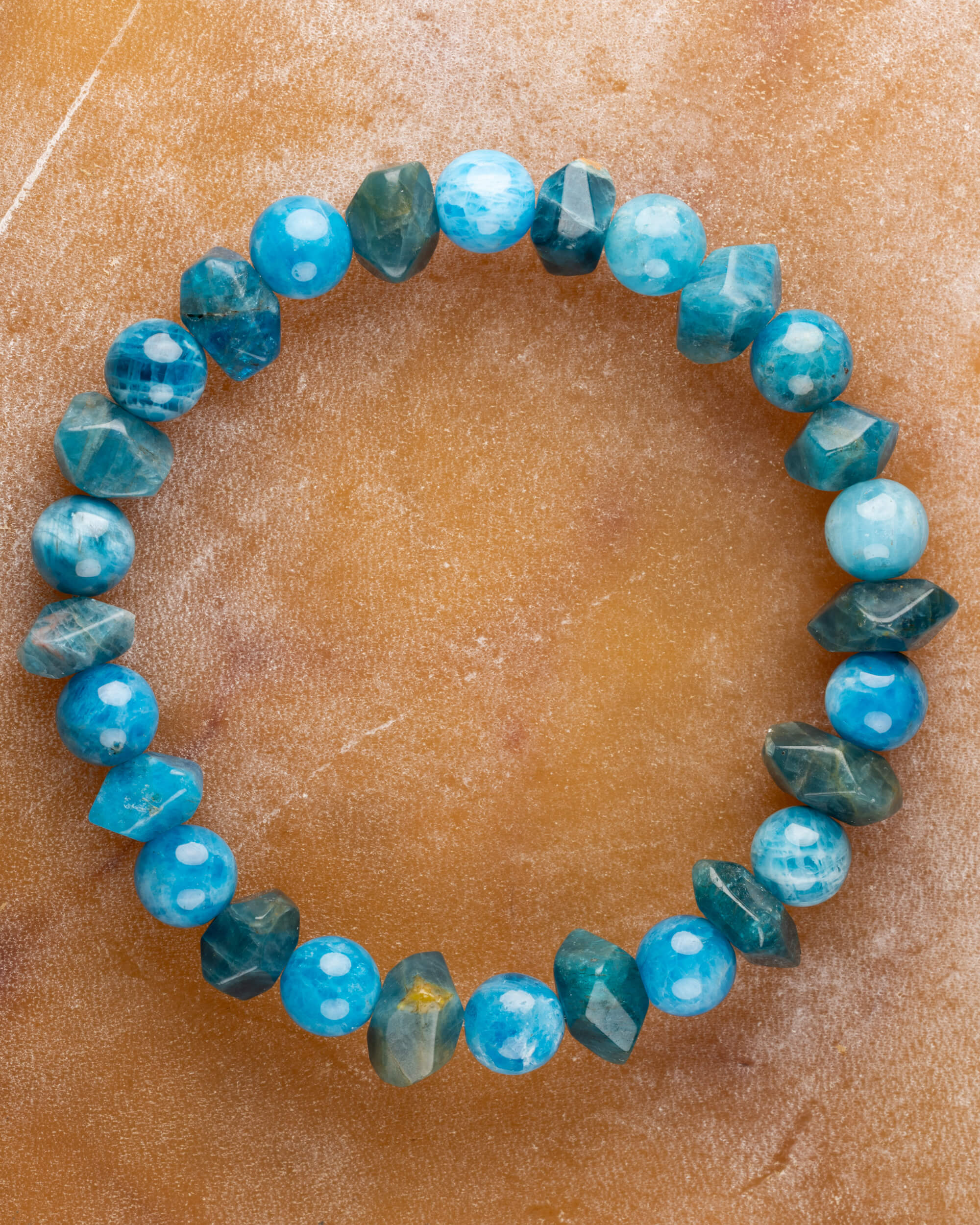 Pulsera de Apatita Azul, pieza completa en círculo sobre superficie color arena