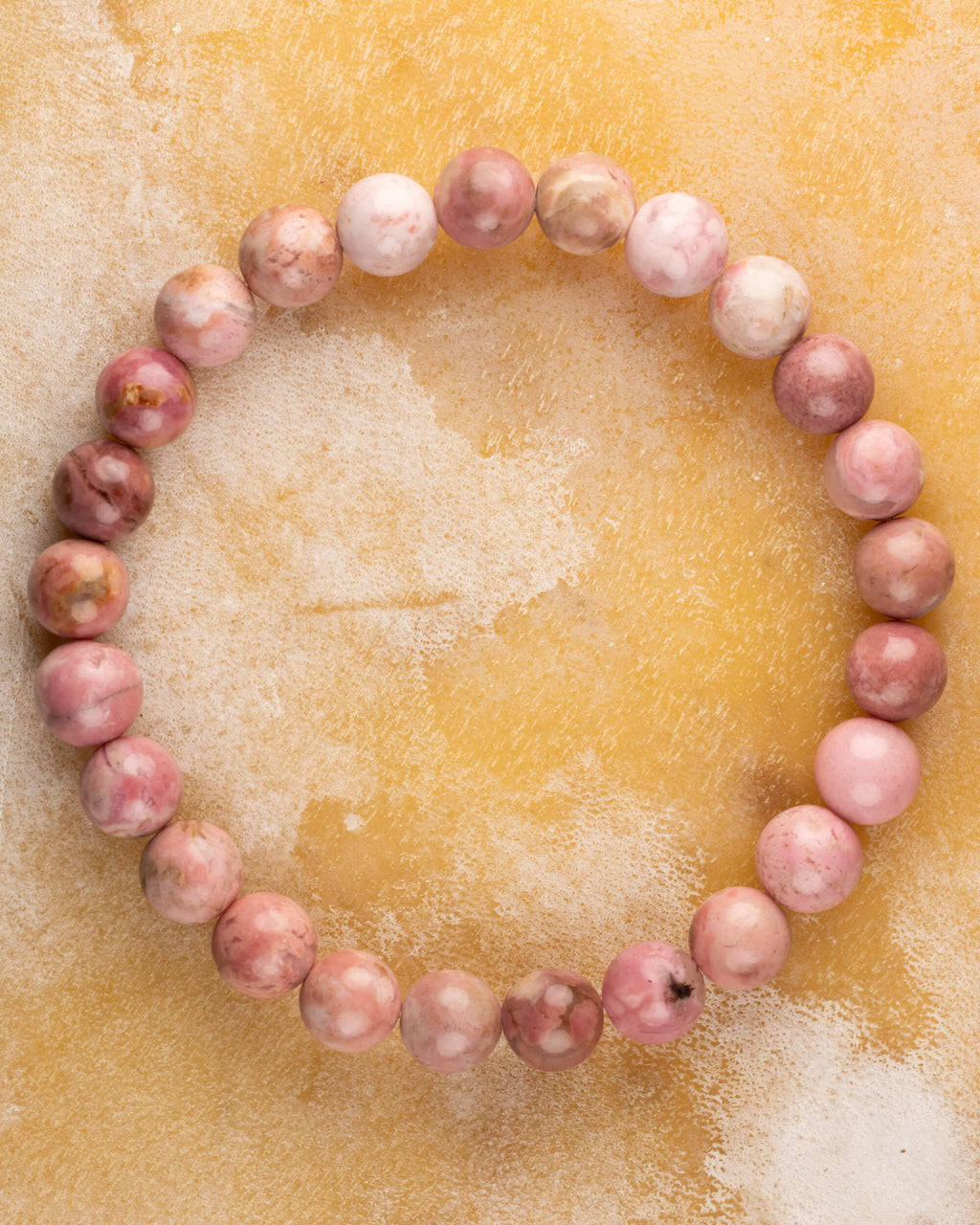 Pulsera de Rodonita Rosa de 8 mm, pieza completa en círculo sobre superficie dorada