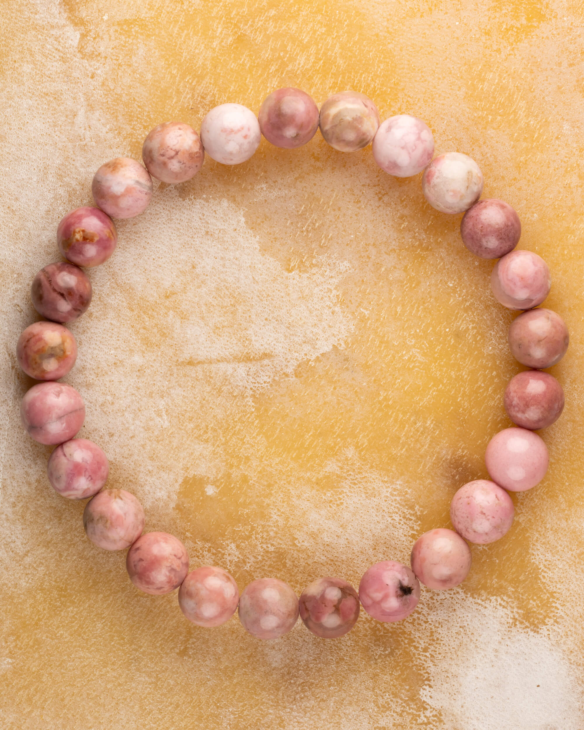 Pulsera de Rodonita Rosa de 8 mm, pieza completa en círculo sobre superficie dorada