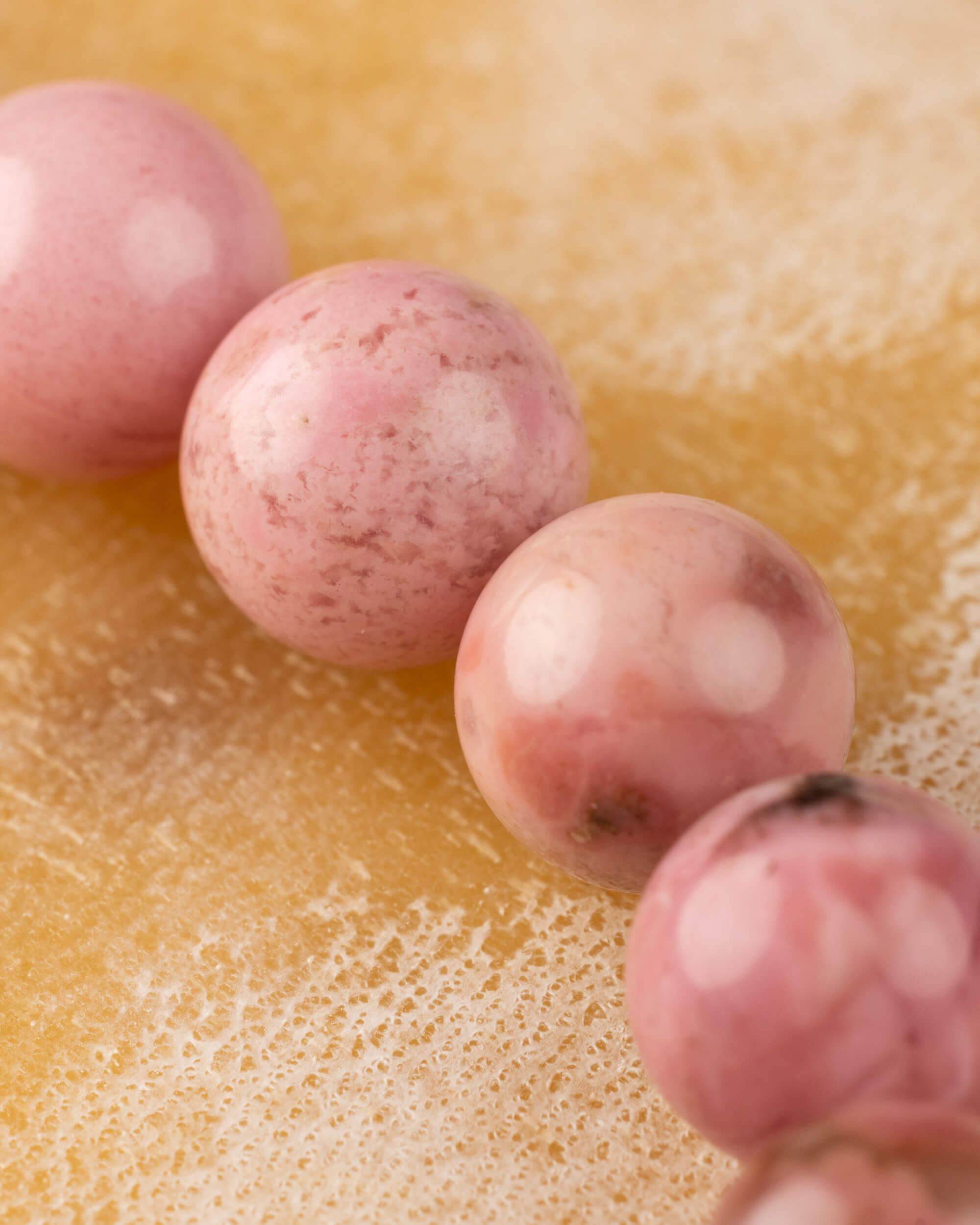 Detalle macro de cuentas de Rodonita Rosa con manchas blancas características