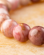 Detalle macro de cuentas de Rodonita Rosa con matices rosados y cafés