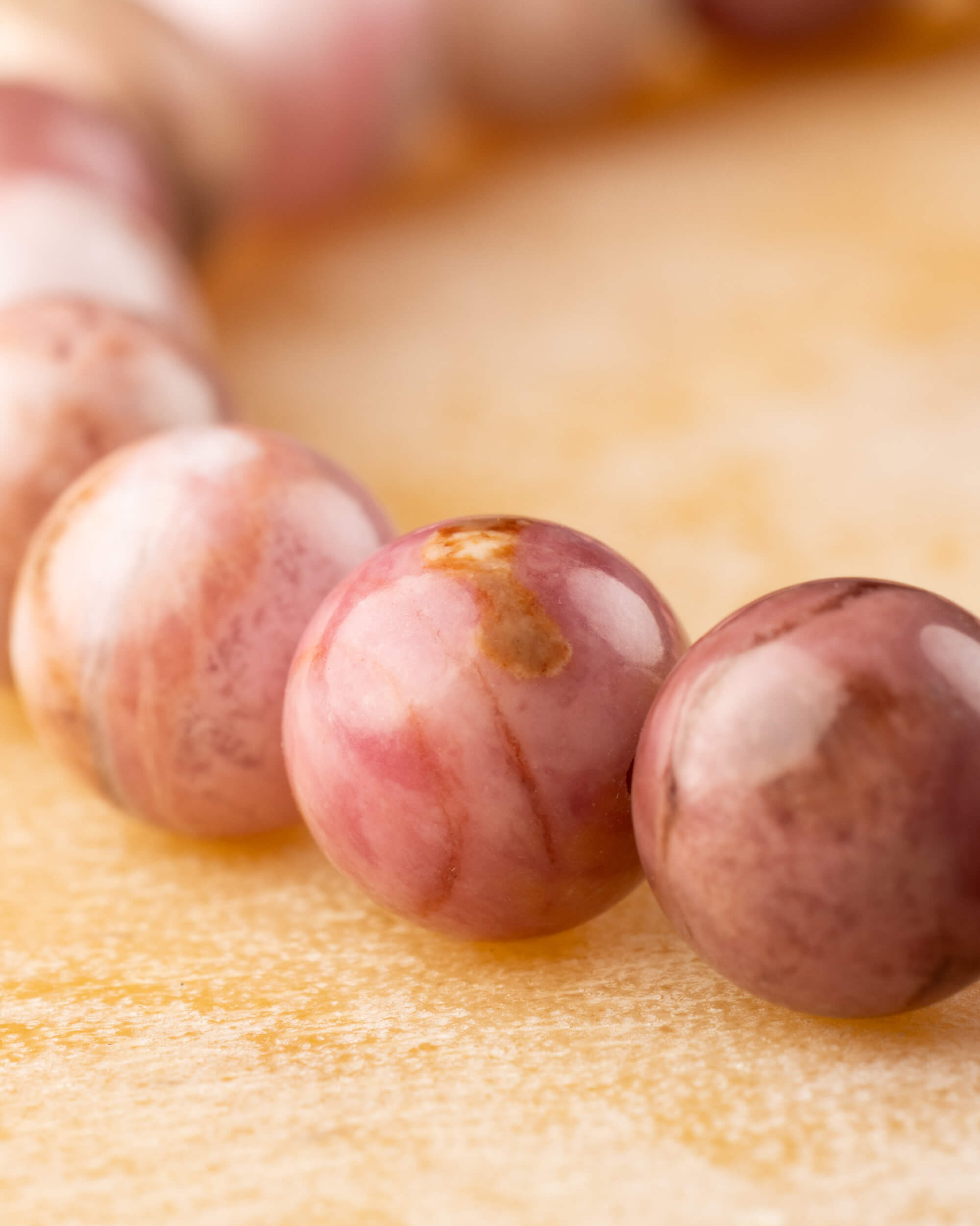 Detalle macro de cuentas de Rodonita Rosa con matices rosados y cafés