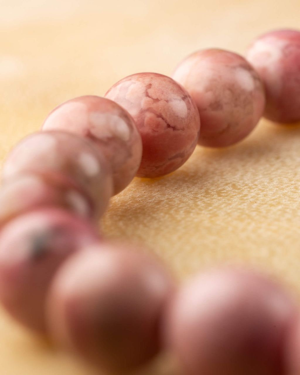 Detalle macro de cuentas de Rodonita Rosa, una con mancha negra natural