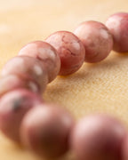 Detalle macro de cuentas de Rodonita Rosa, una con mancha negra natural
