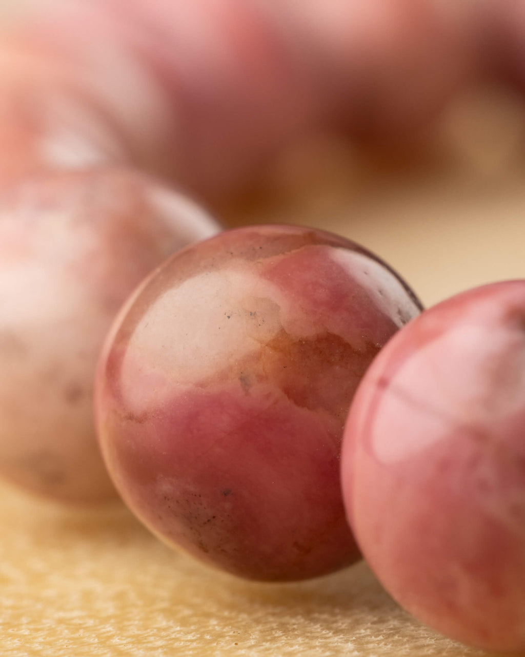 Detalle macro de una cuenta de Rodonita Rosa con manchas blancas redondas