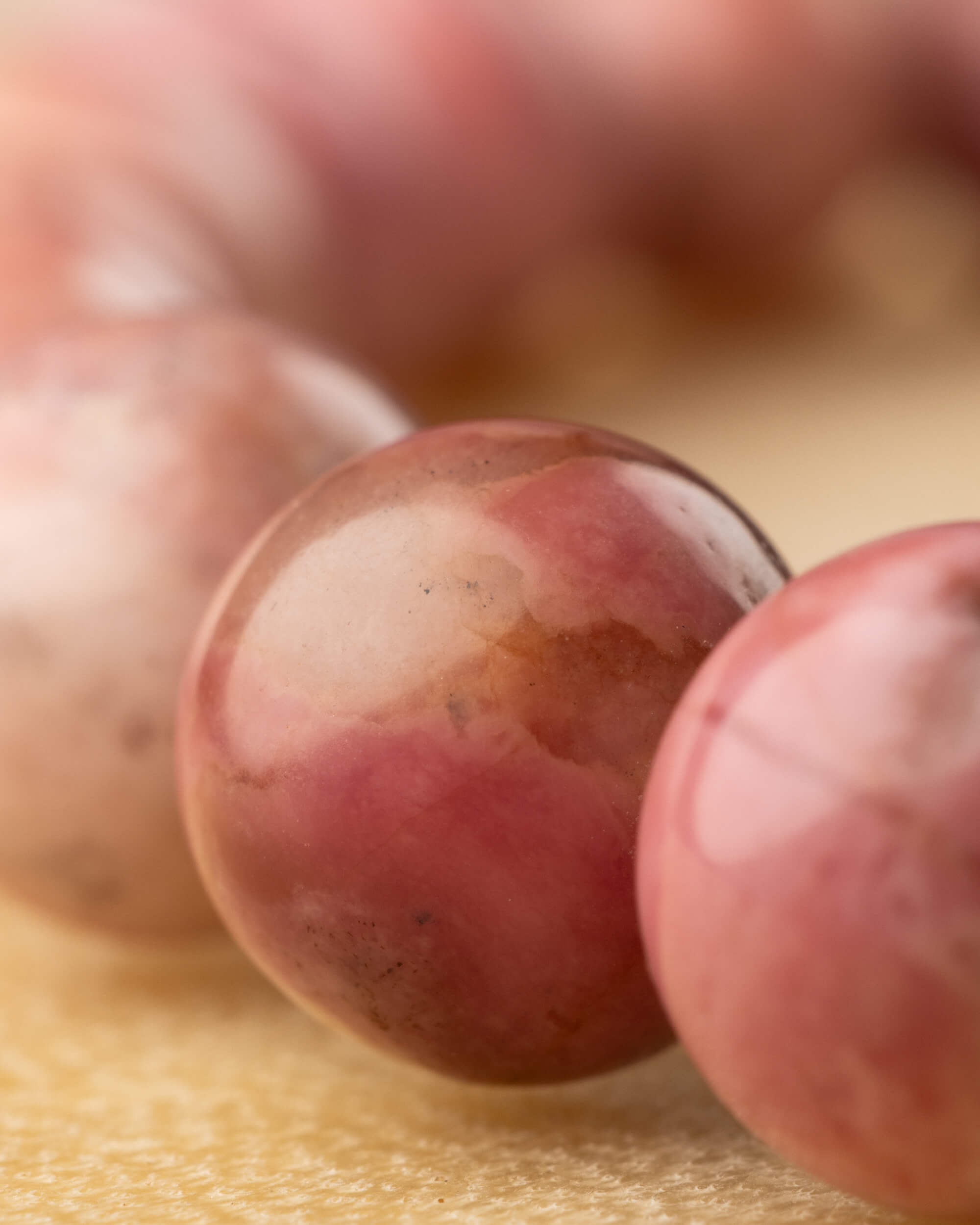 Detalle macro de una cuenta de Rodonita Rosa con manchas blancas redondas