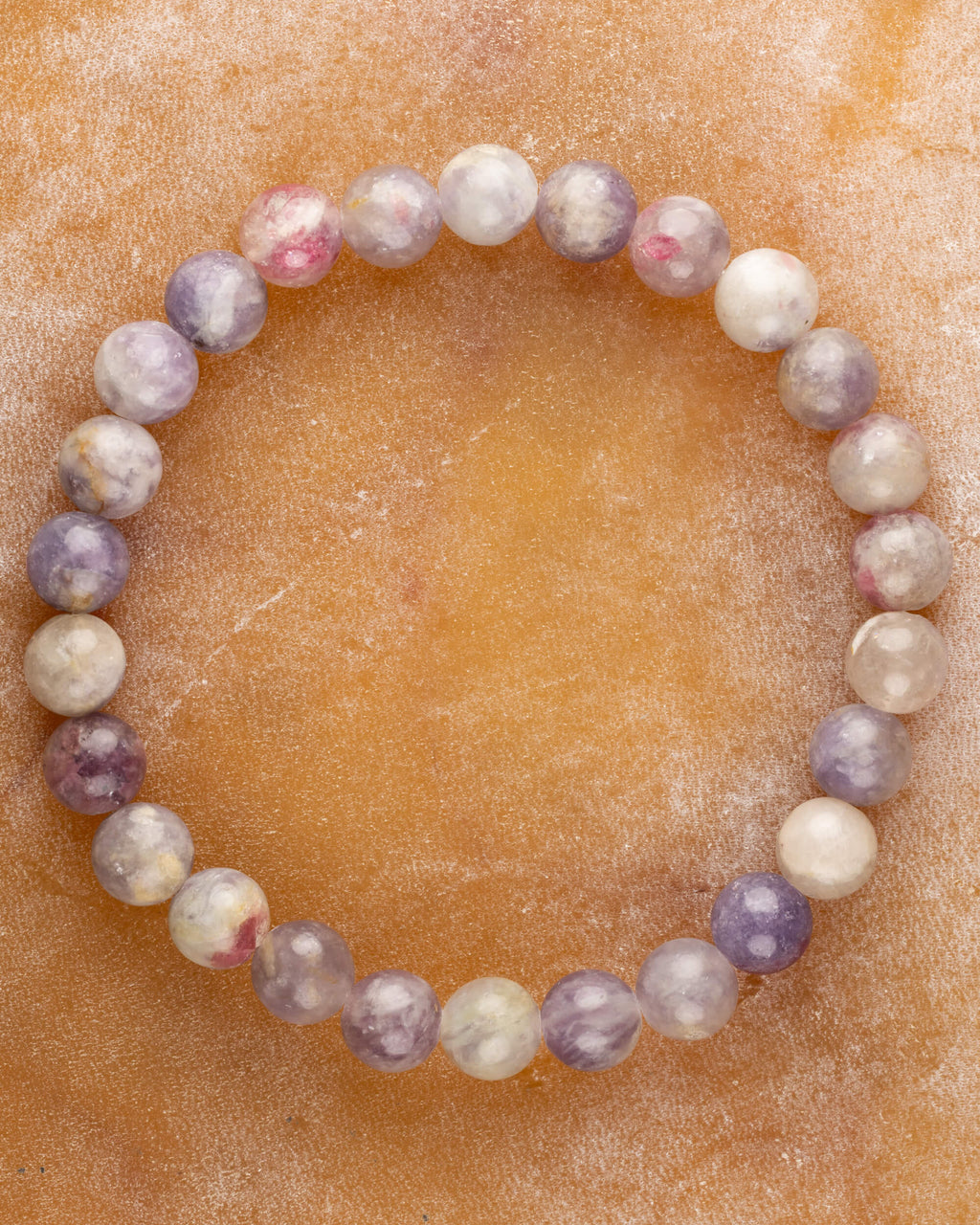 Pulsera de Turmalina Rosa de 8 mm, pieza completa en círculo sobre superficie de mármol color miel