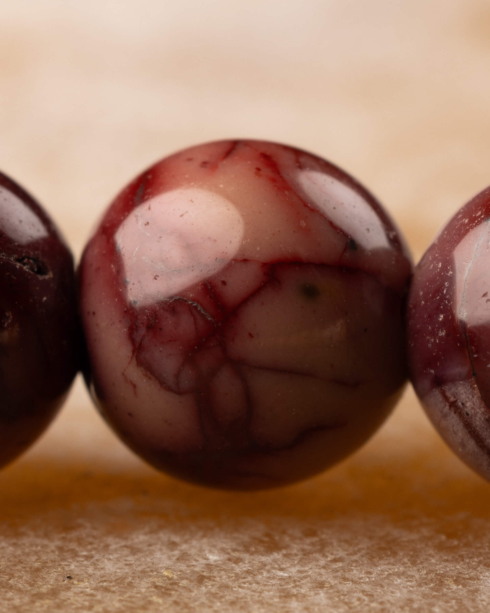 Detalle macro de cuentas de Jaspe Mokaita en tono vino con vetas rojas