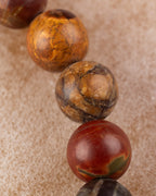 Detalle macro de cuentas de Jaspe Picasso ocre y roja sobre superficie clara