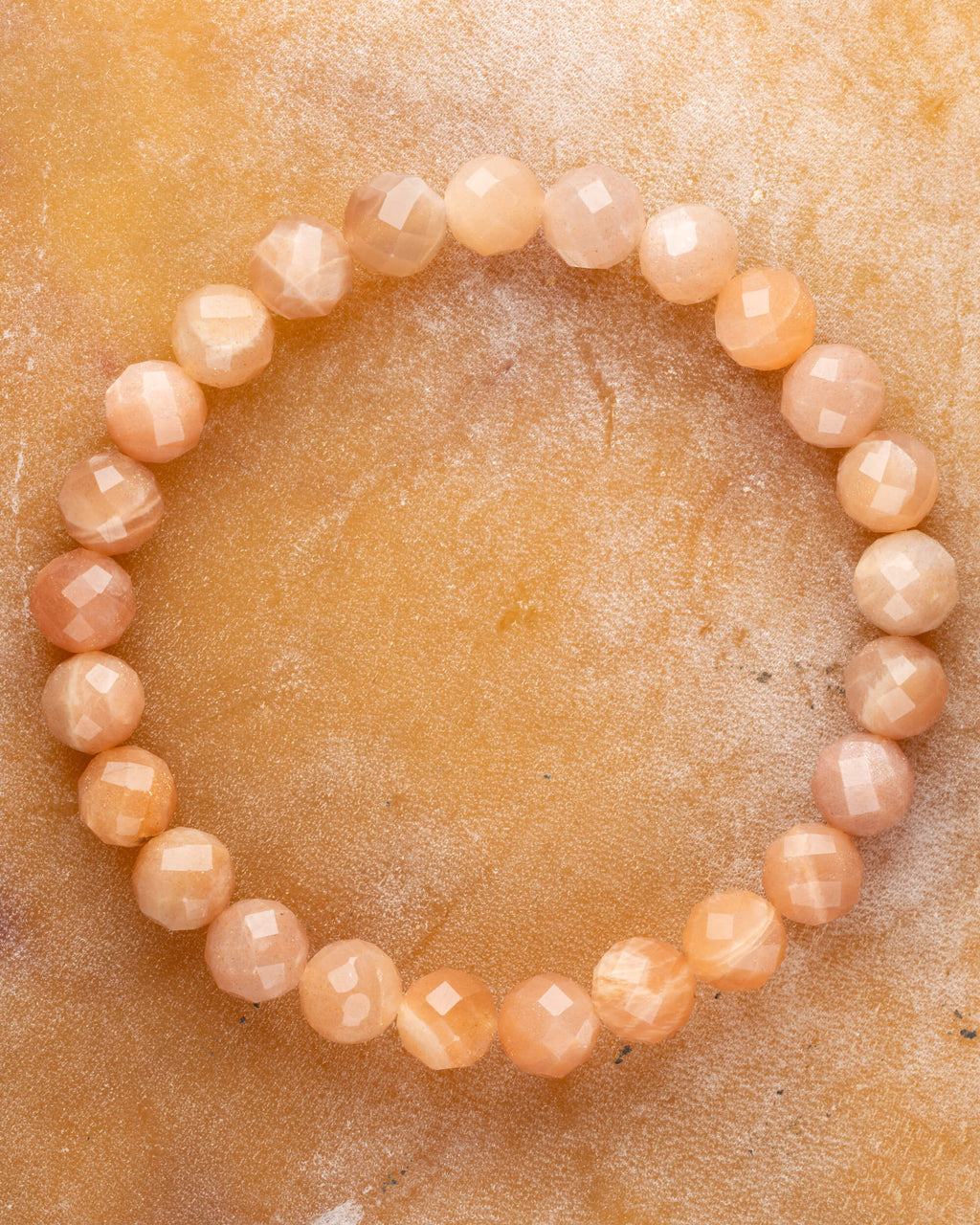 Pulsera de Piedra Sol Naranja facetada de 8 mm, pieza completa en círculo sobre superficie dorada