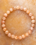 Pulsera de Piedra Sol Naranja facetada de 8 mm, pieza completa en círculo sobre superficie dorada