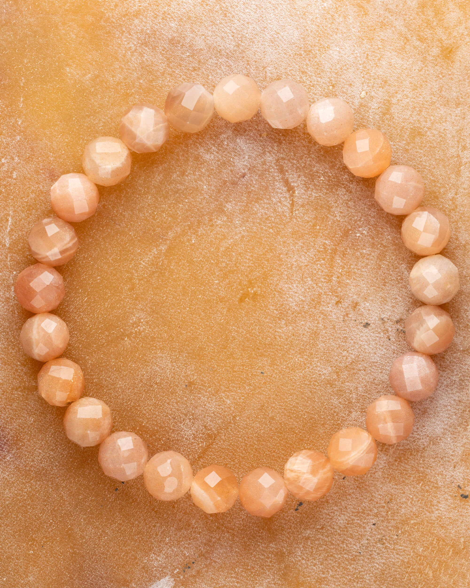 Pulsera de Piedra Sol Naranja facetada de 8 mm, pieza completa en círculo sobre superficie dorada