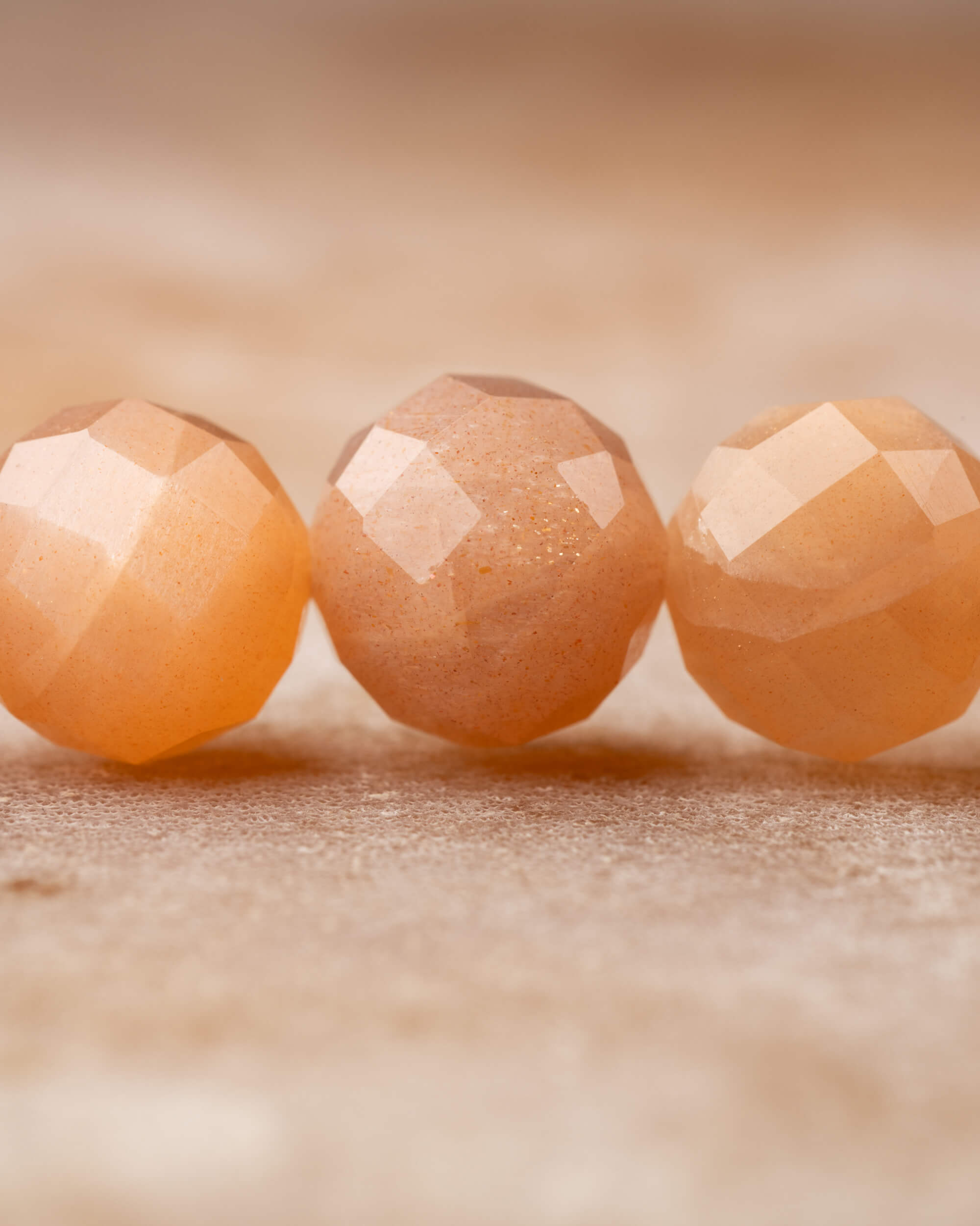 Detalle macro de las cuentas facetadas de Piedra Sol Naranja con destellos dorados