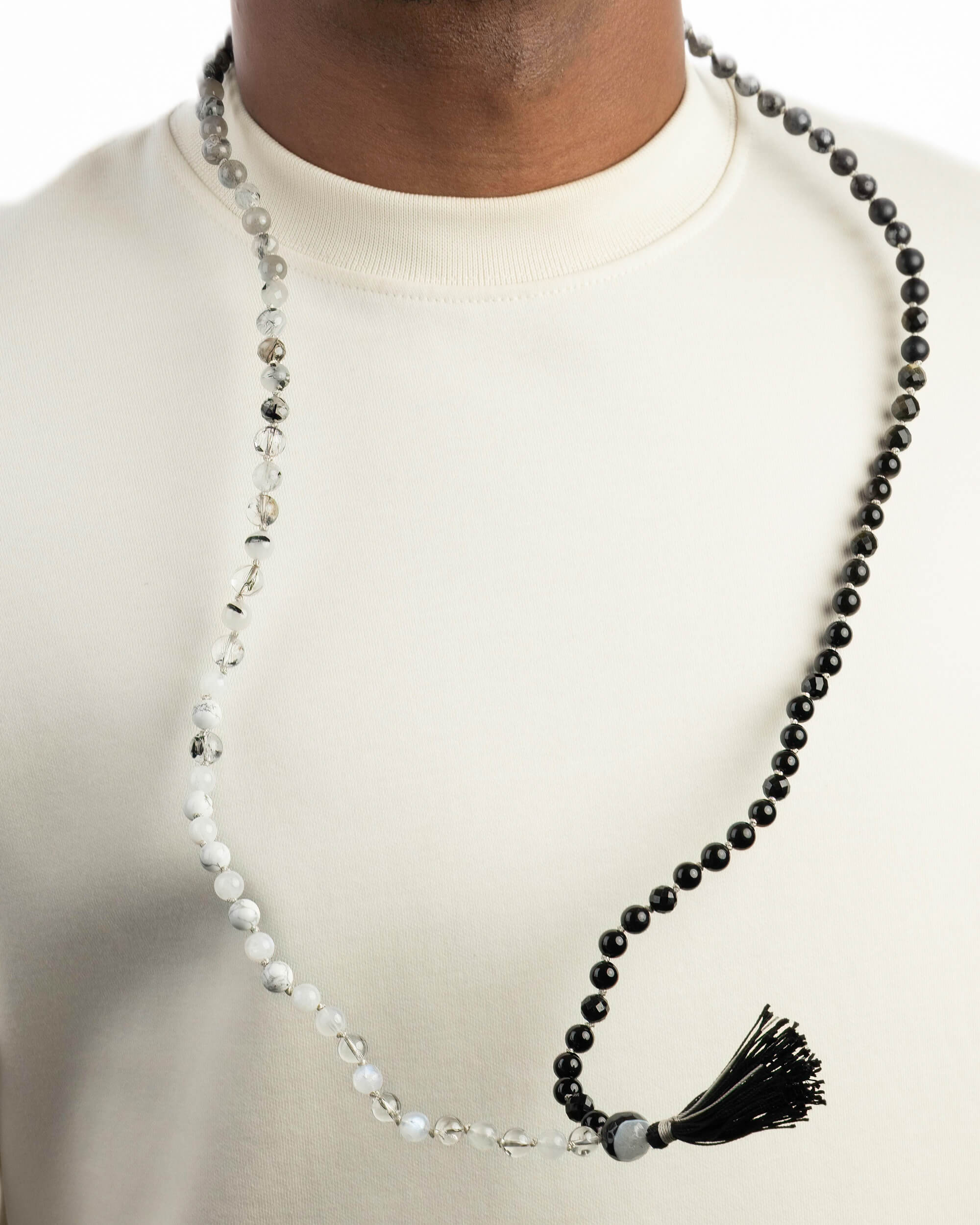 Japa Mala Dualidad puesto en el cuello, cuentas en degradado de gris a negro con borla negra