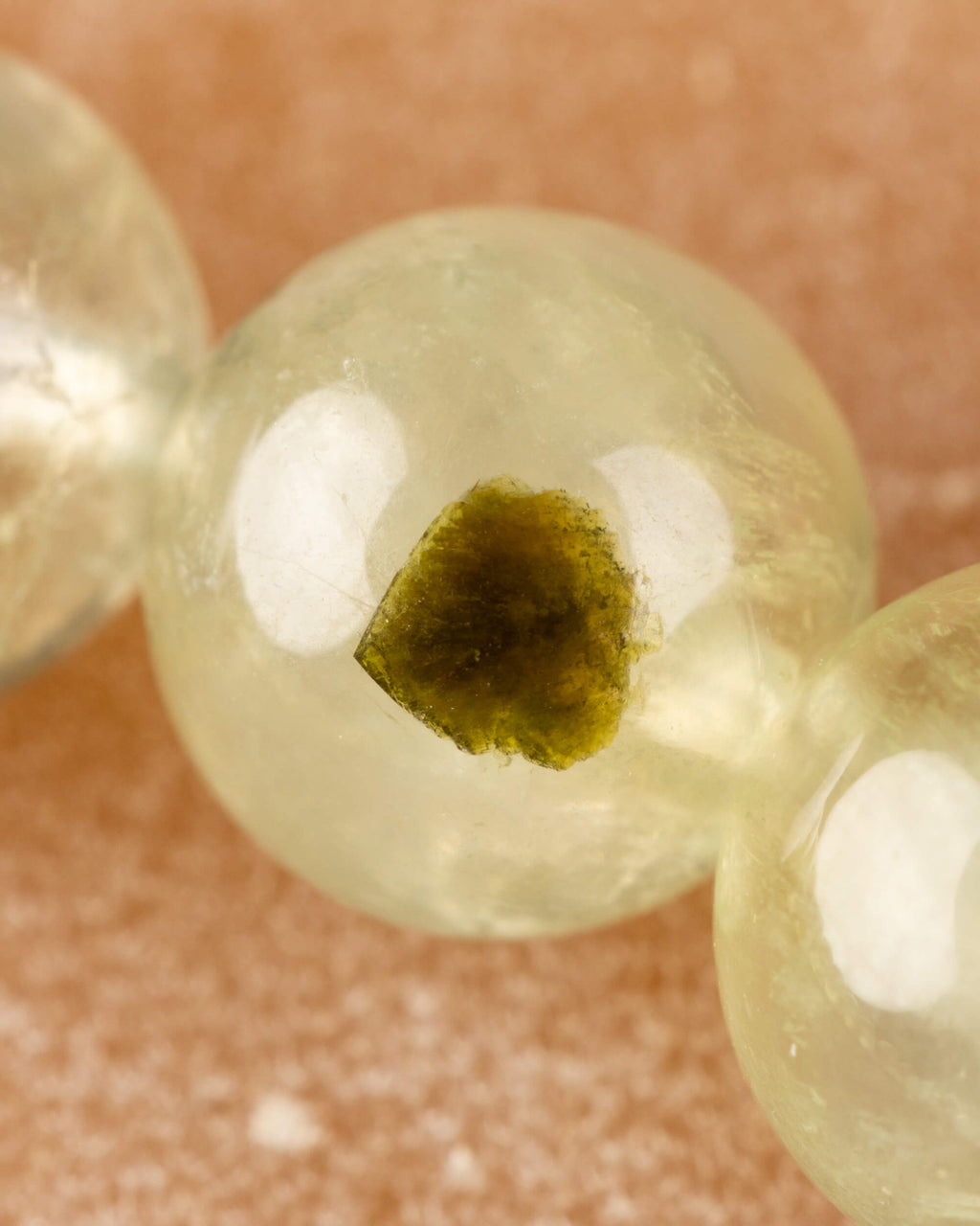 Detalle macro de una cuenta de Prehnita transparente con inclusión verde oscura