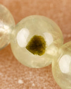 Detalle macro de una cuenta de Prehnita transparente con inclusión verde oscura