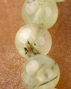 Detalle macro de una cuenta de Prehnita con inclusión oscura entre cuentas claras