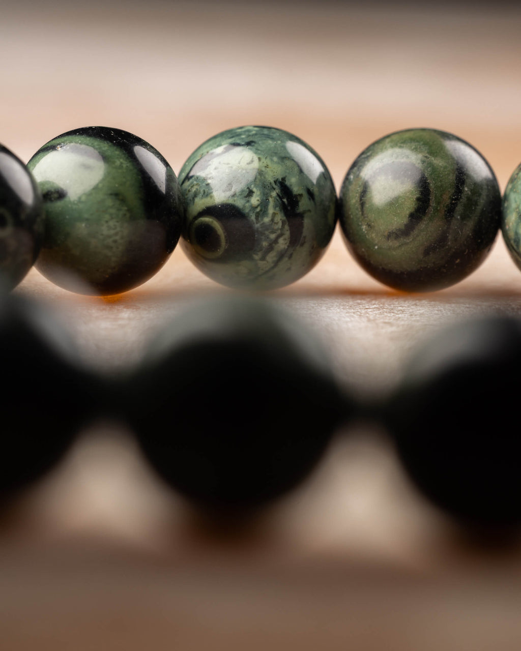 Pulsera de Jaspe Kambaba vista de lado con cuentas negras difuminadas abajo