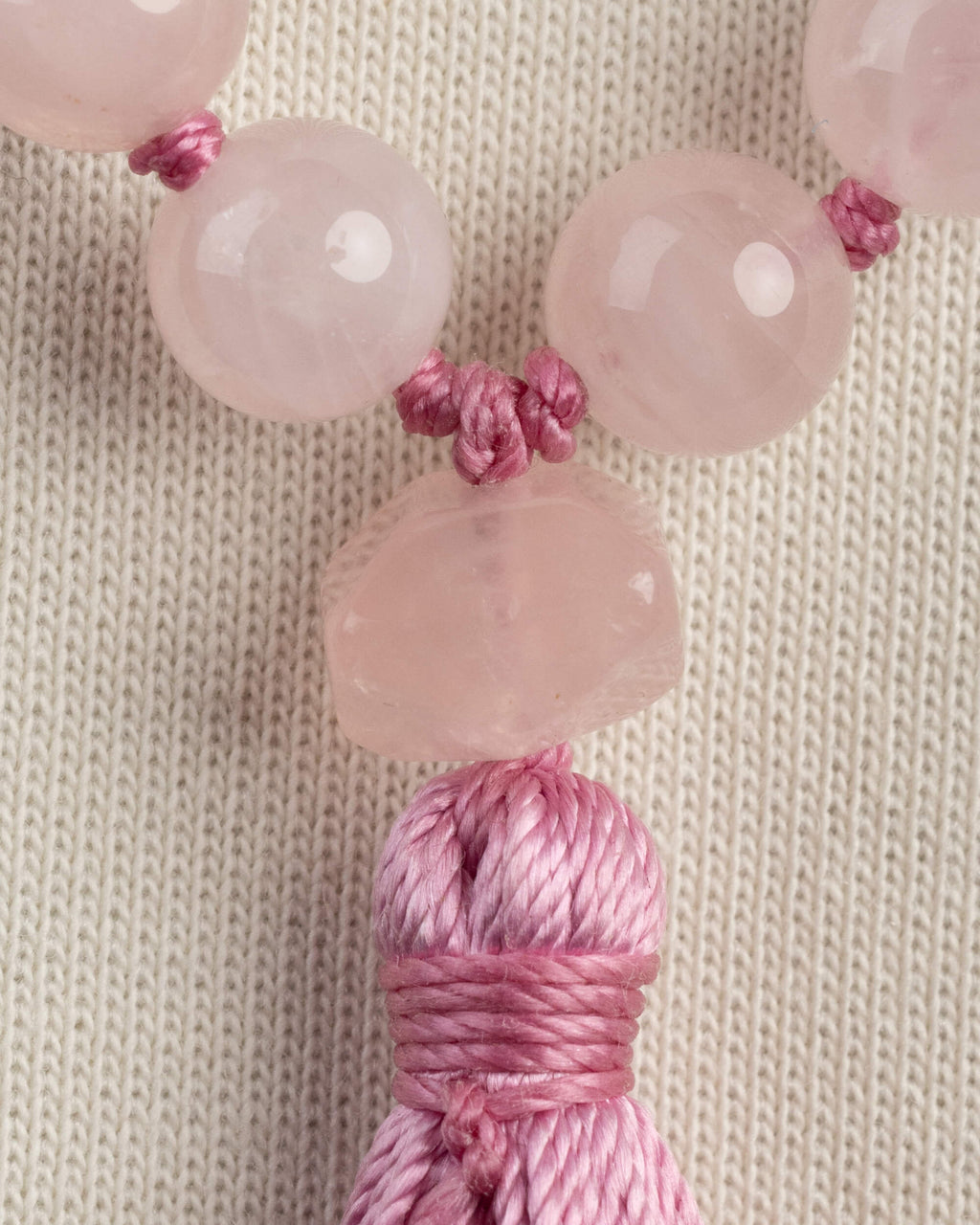 Detalle macro de las cuentas de Cuarzo Rosa junto al borlón rosa
