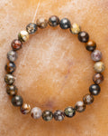 Pulsera de Pietersita multicolor de 8 mm, pieza completa en círculo sobre superficie miel