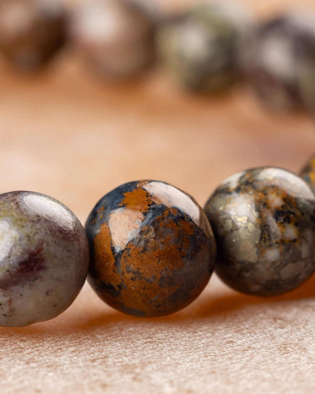 Detalle macro de cuentas de Pietersita con manchas cafés, naranjas y grises