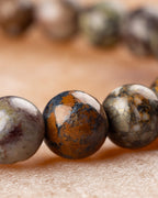 Detalle macro de cuentas de Pietersita con manchas cafés, naranjas y grises