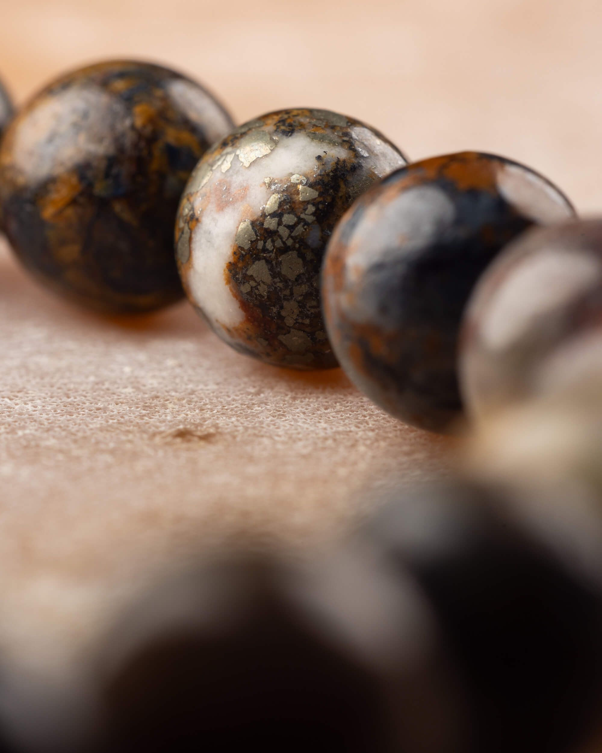 Detalle macro de cuentas de Pietersita con vetas doradas, negras y beige moteado