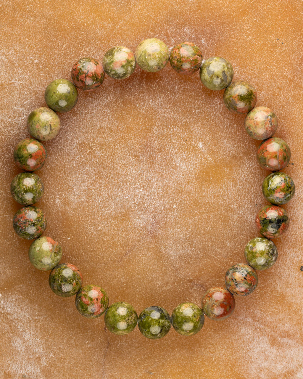 Pulsera de Jaspe Unakita de 8 mm, pieza completa sobre superficie ocre