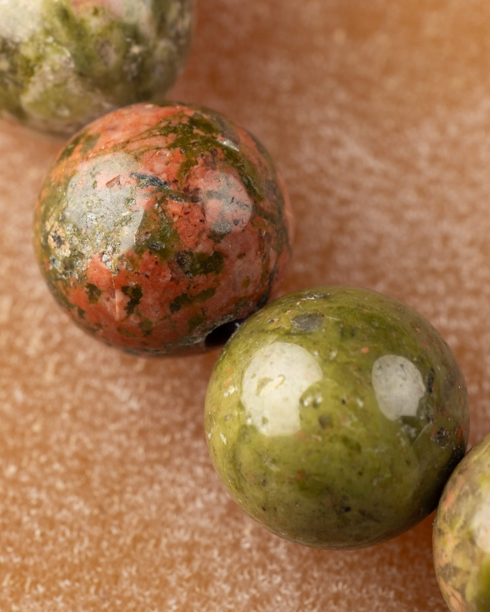 Detalle macro de dos cuentas de Jaspe Unakita, una verde y una terracota