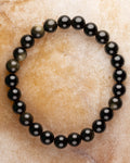 Pulsera de Obsidiana Dorada de 8 mm, pieza completa sobre superficie de mármol claro