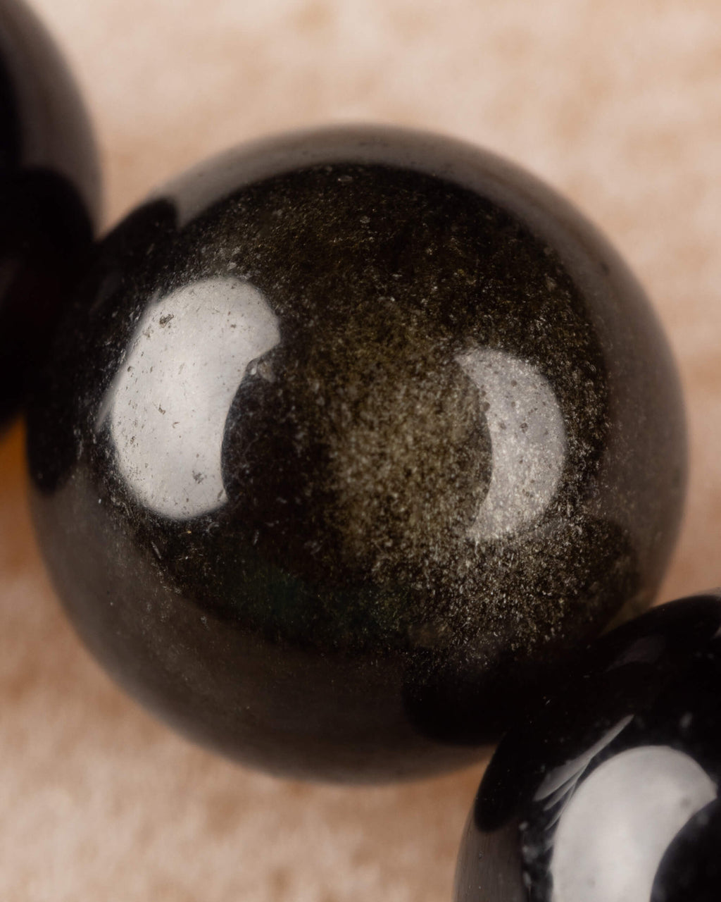 Detalle macro de cuenta de Obsidiana Dorada con destellos dorados visibles