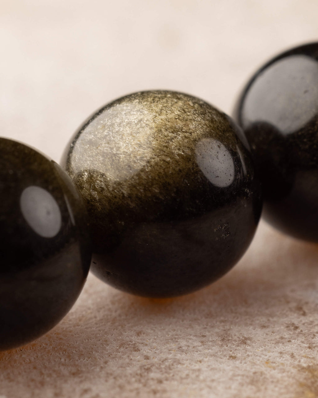 Detalle macro de cuenta de Obsidiana Dorada, con su brillo dorado característico