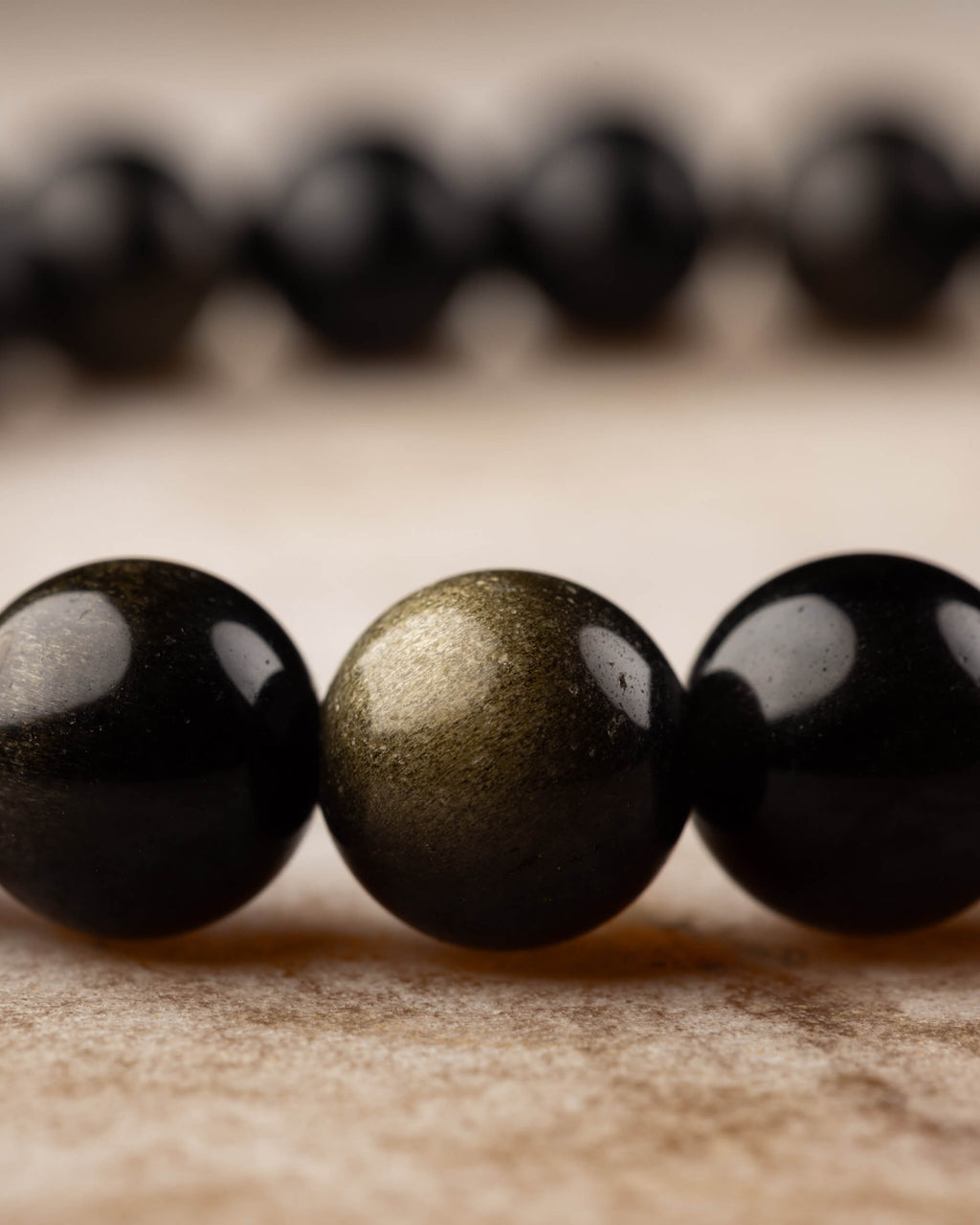 Pulsera de Obsidiana Dorada en ángulo bajo, cuentas negras con destello dorado