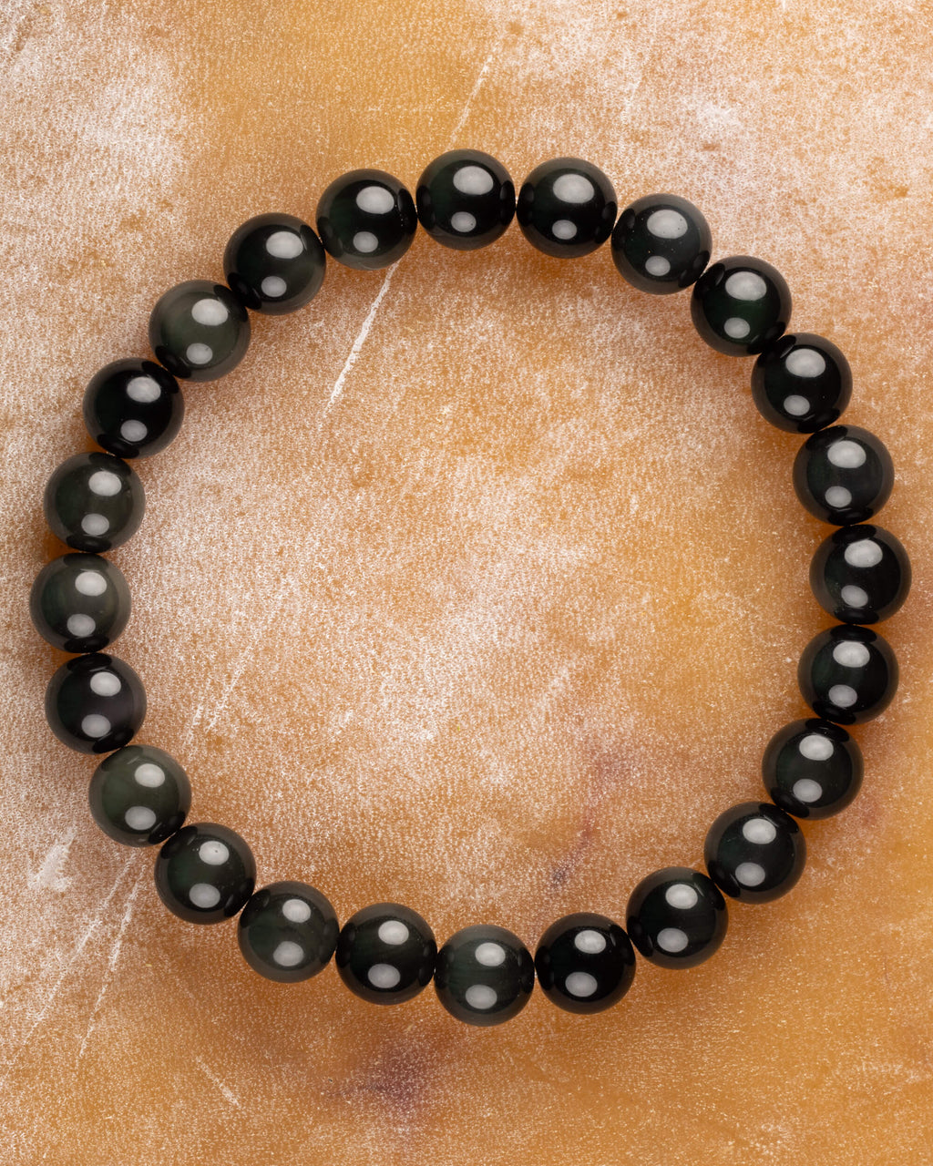 Pulsera de Obsidiana Arcoíris de 8 mm, pieza completa sobre superficie ámbar clara