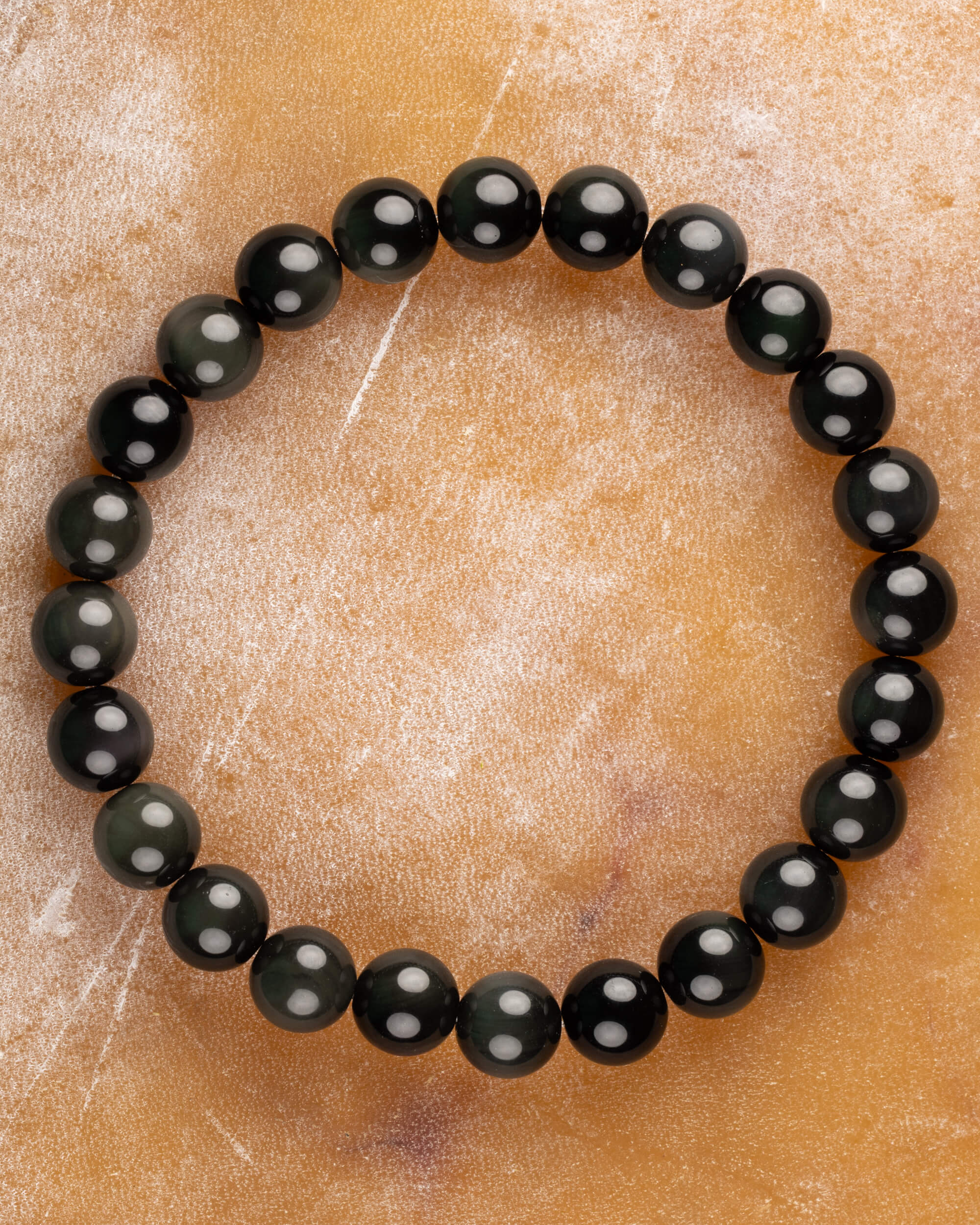 Pulsera de Obsidiana Arcoíris de 8 mm, pieza completa sobre superficie ámbar clara