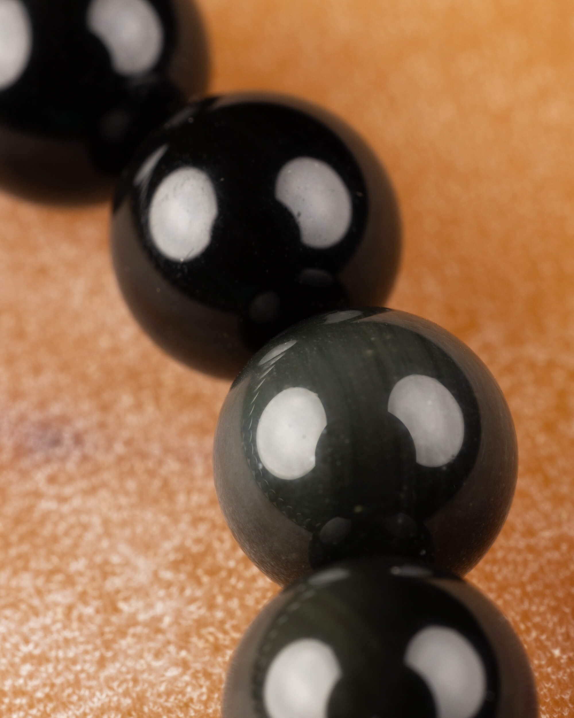 Cuentas de Obsidiana Arcoíris en fila, alternando negro profundo y reflejo verdoso
