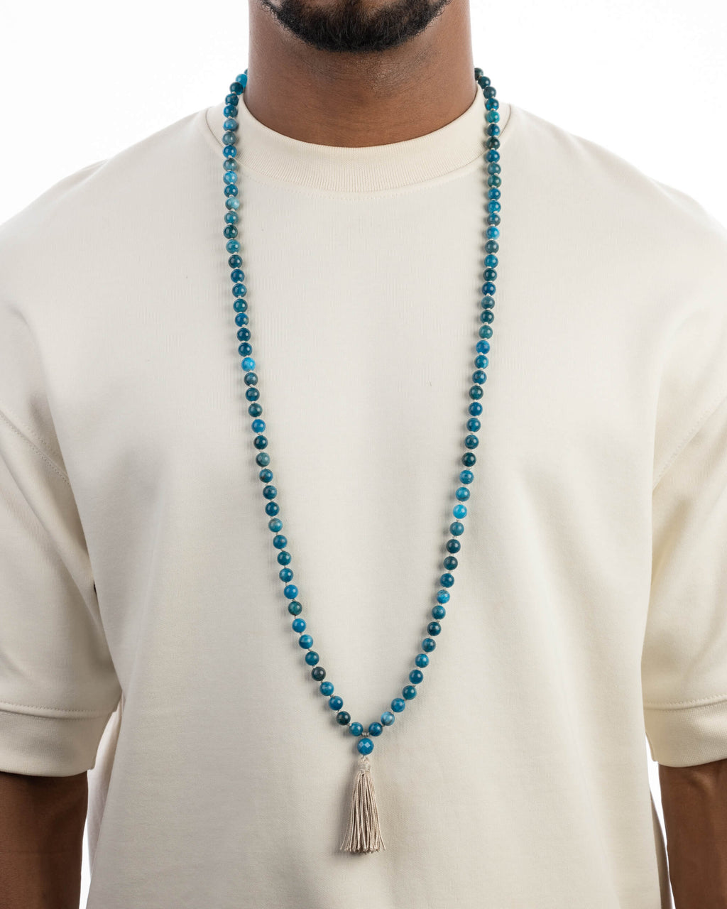 Japa Mala de Apatita Azul puesto, cayendo sobre el pecho con playera clara