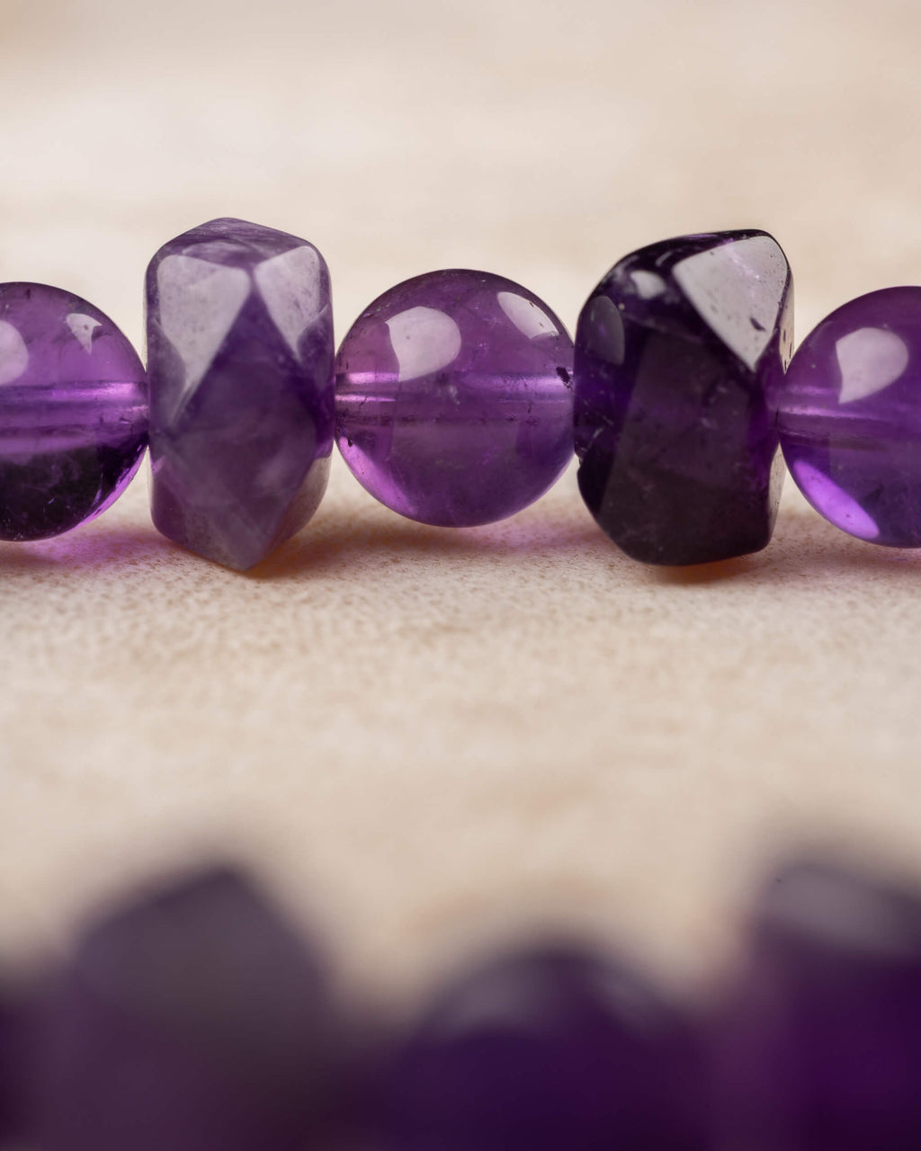 Detalle macro de cuentas de Amatista facetadas y redondas con brillo morado