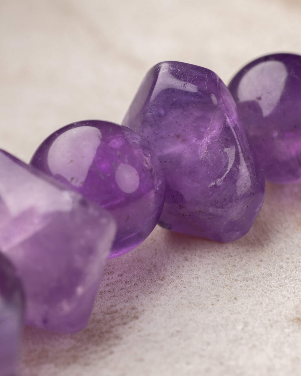 Detalle macro de cuentas facetadas de Amatista con brillo morado intenso