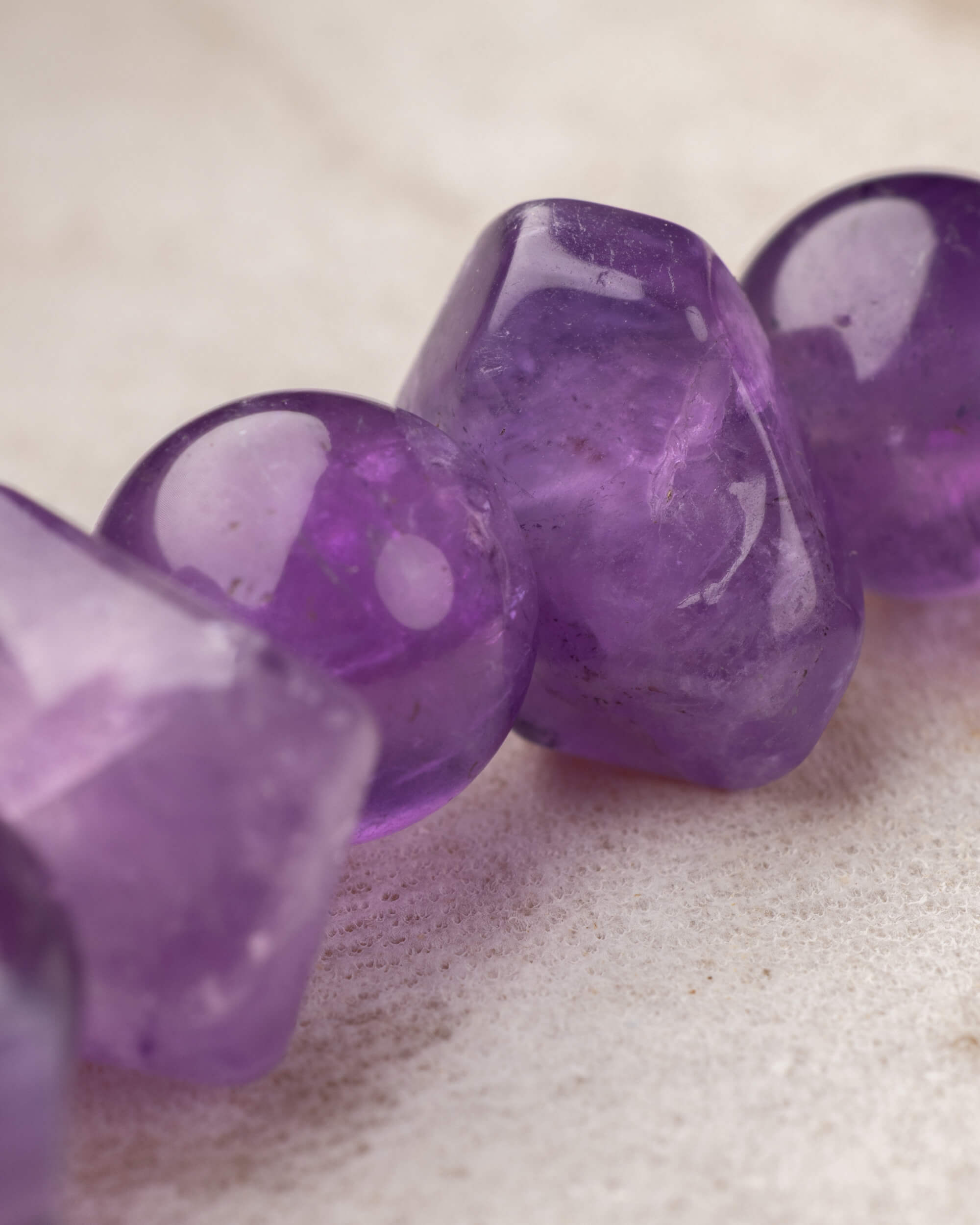 Detalle macro de cuentas facetadas de Amatista con brillo morado intenso