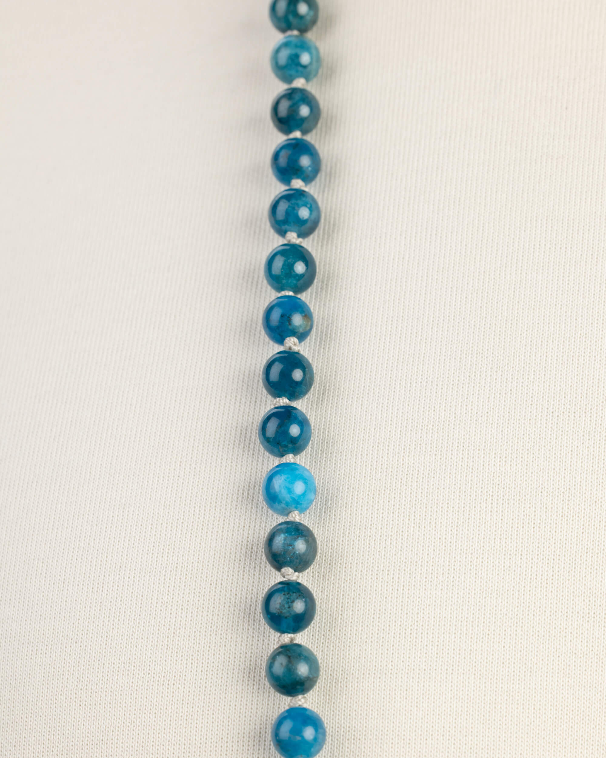 Japa Mala de Apatita Azul en fila vertical, cuentas sobre playera clara