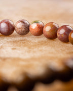 Pulsera de Jaspe Oceánico curvada mostrando cuentas en tonos rojo y ocre