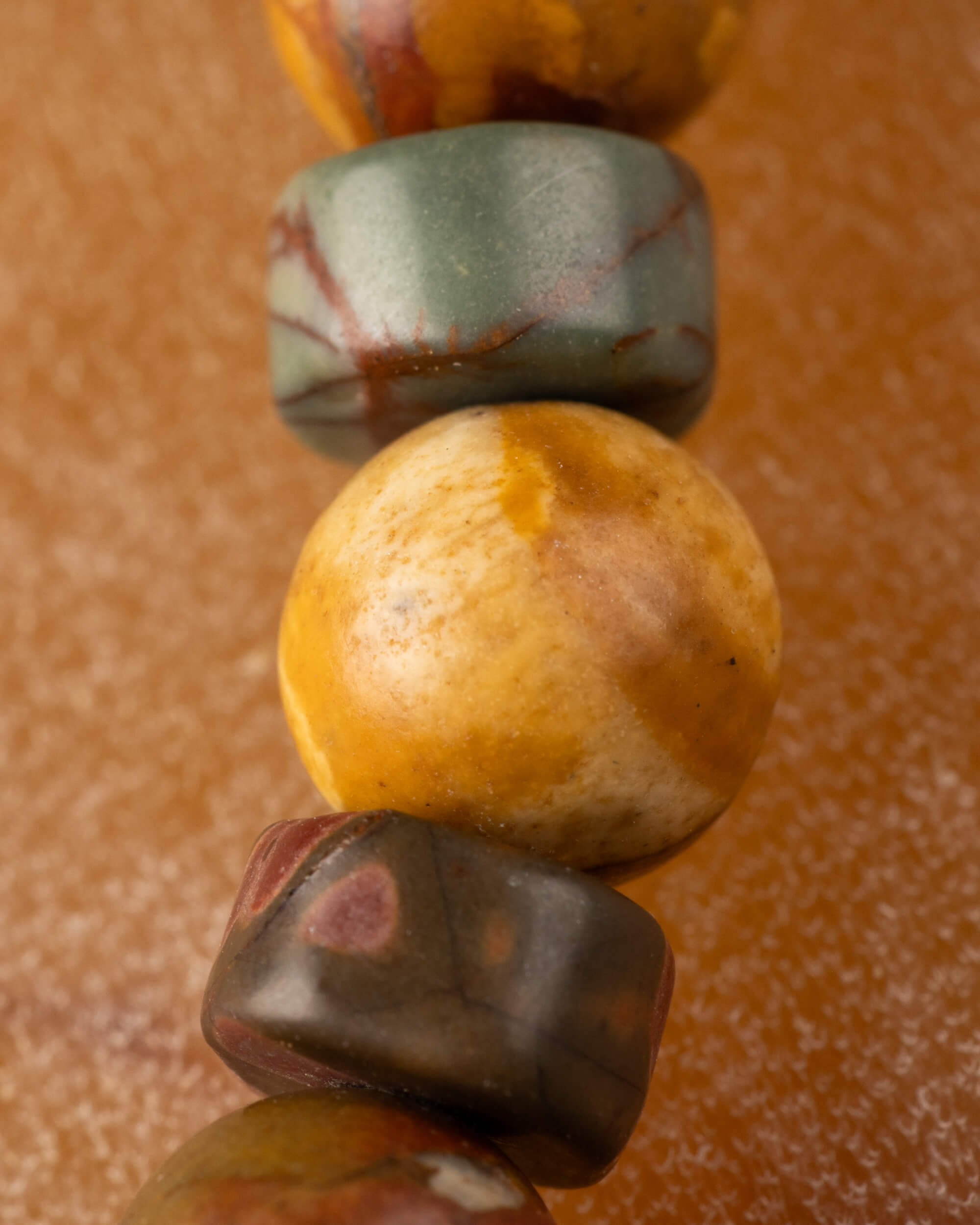 Detalle macro de cuentas de Jaspe Picasso con disco verde y esfera ocre