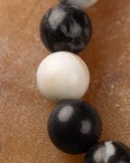Detalle macro de una cuenta blanca lisa entre cuentas negras del Jaspe Cebra