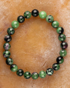 Pulsera de Zoisita completa en círculo sobre superficie color canela, cuentas verdes y negras