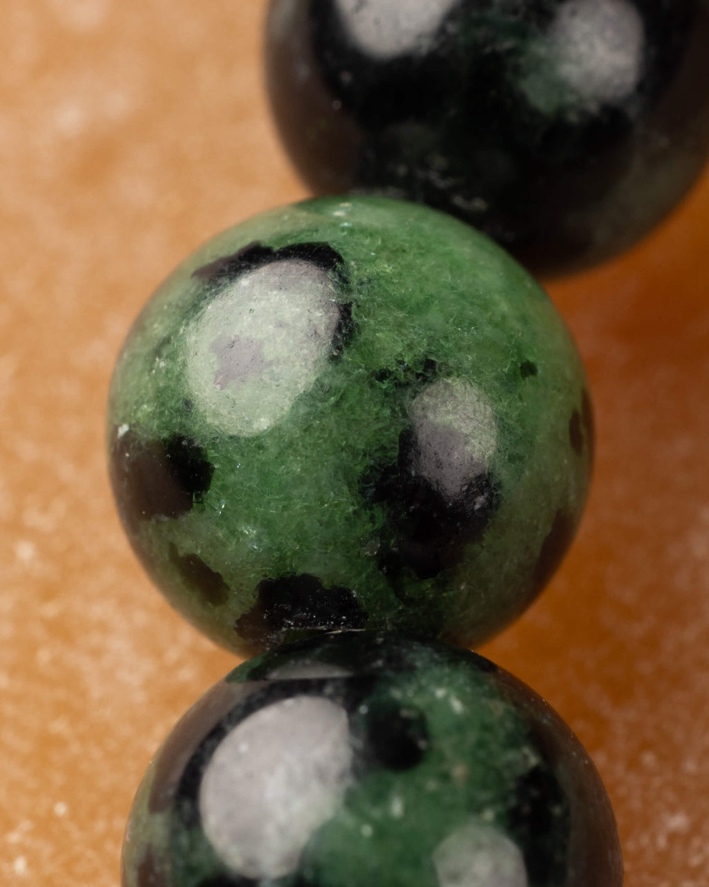 Macro de una cuenta de Zoisita verde con manchas negras y blancas de la pulsera